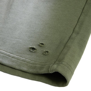 Close-up of a green fabric with three small holes on a white background