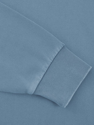 Close-up of the ribbed cuff on the sleeve of the 360 GSM vintage-washed cotton crewneck in jeans blue