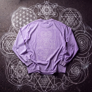 Back of the Mystic Myco acid wash oversized long sleeve tee in Purple, styled on dark asphalt covered in white chalk sacred geometry, showing a fine-line tarot panel of constellations, a faceted crystal, a central mandala and moon phases inside a thin border.