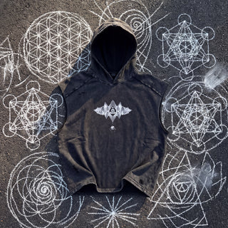 Front of the Mycelial Network snow washed boxy hooded tank top in black, hood open, styled on dark asphalt covered in white chalk sacred geometry, showing the small silver crystal emblem with a meditating figure on the chest.