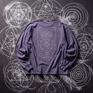 Back of the Mystic Myco acid wash oversized long sleeve tee in Purple Haze, styled on dark asphalt covered in white chalk sacred geometry, showing a fine-line tarot panel of constellations, a faceted crystal, a central mandala and moon phases inside a thin border.