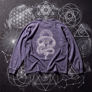 Back of the Ouroboros Gate acid wash oversized long sleeve tee in Purple Haze, styled on dark asphalt covered in white chalk sacred geometry, showing a skeletal serpent coiled beneath a ring gate.