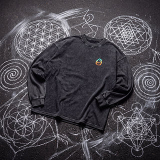Front of the Paradigm acid wash oversized long sleeve tee in Black Beauty, styled on dark asphalt covered in white chalk sacred geometry, with the Phantasmagorical logo on the left chest.
