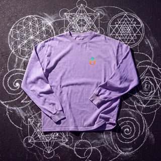 Front of the Paradigm acid wash oversized long sleeve tee in Purple, styled on dark asphalt covered in white chalk sacred geometry, with the Phantasmagorical logo on the left chest.