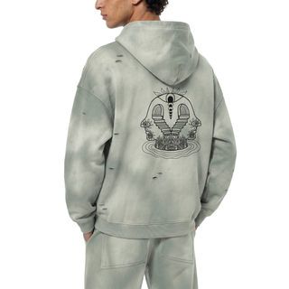 Model seen from behind wearing the Enigma sunfade frayed fleece hoodie in Light Gray with matching sweatpants, showing the oversized drop-shoulder fit and the Enigma back print in black line art