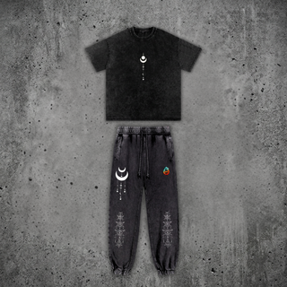 Existential Snow Wash Set by Phantasmagorical — black snow-wash oversized heavyweight tee and matching joggers, front view, with minimalist white celestial moon-phase graphics on the chest and thigh.
