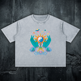 Light gray mineral wash Yin Yang boxy tee on dark concrete, cropped fit, printed with teal hands cradling a sun-rayed yin-yang, planets and a UFO.