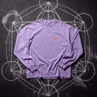 Front of the PsySquatch acid wash oversized long sleeve tee in Purple, styled on dark asphalt covered in white chalk sacred geometry, with the Phantasmagorical logo on the left chest.