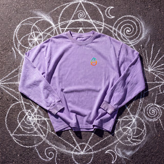 Front of the Spirit Animal acid wash oversized long sleeve tee in Purple, styled on dark asphalt covered in white chalk sacred geometry, with the Phantasmagorical logo on the left chest.