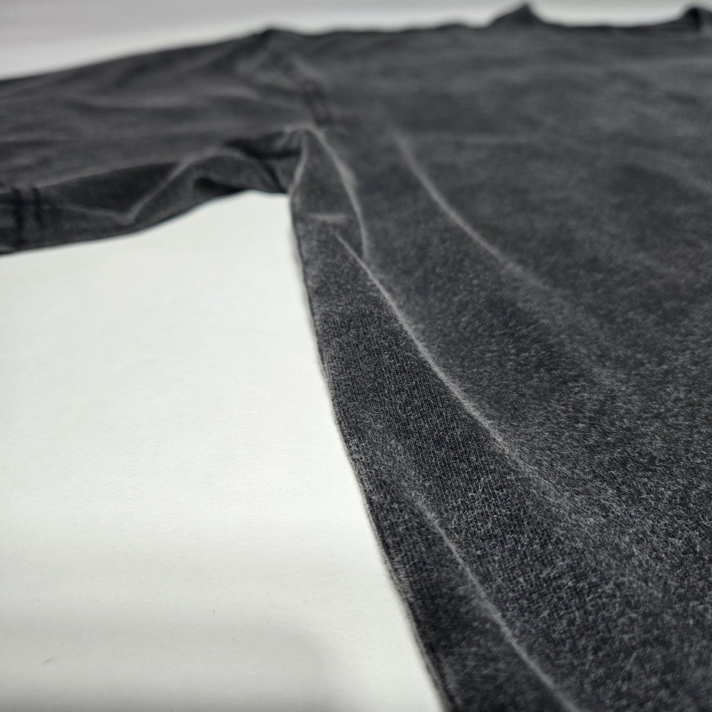 Side angle flat lay of Spectral Knight Fluffy Vintage tee showing charcoal snow wash finish
