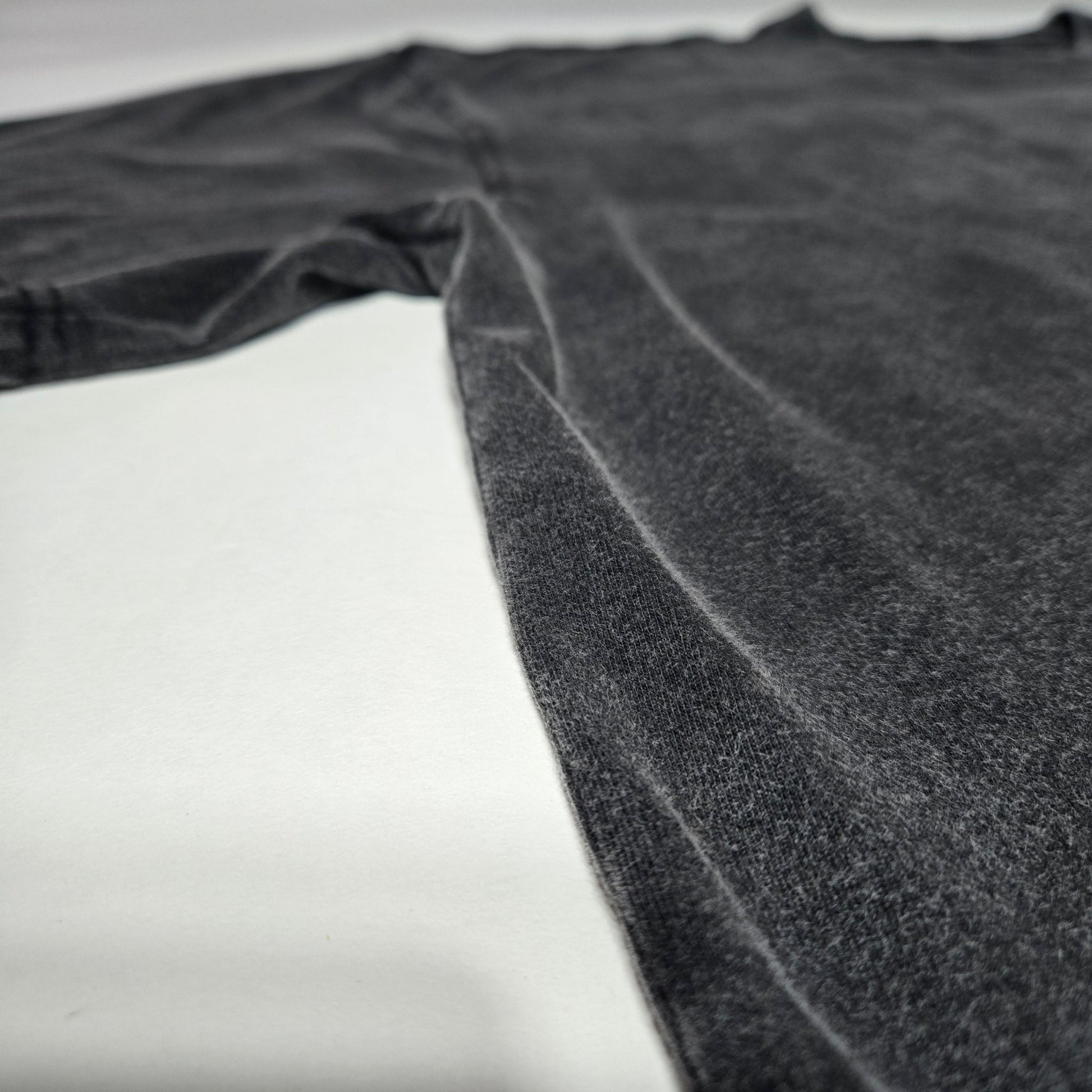 Side angle flat lay of Spectral Knight Fluffy Vintage tee showing charcoal snow wash finish