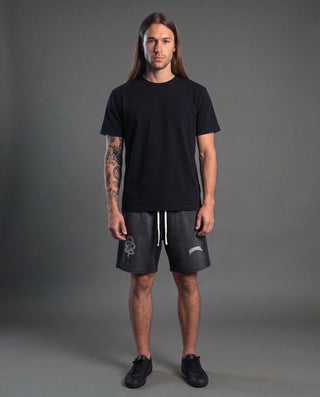 Model wearing the Spirit Molecule sun fade heavyweight distressed shorts in Black, front view, showing the serpent graphic and the Phantasmagorical wordmark.